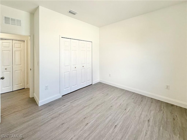 unfurnished bedroom with light hardwood / wood-style flooring and a closet