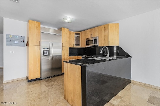 kitchen with appliances with stainless steel finishes, sink, decorative backsplash, and dark stone countertops