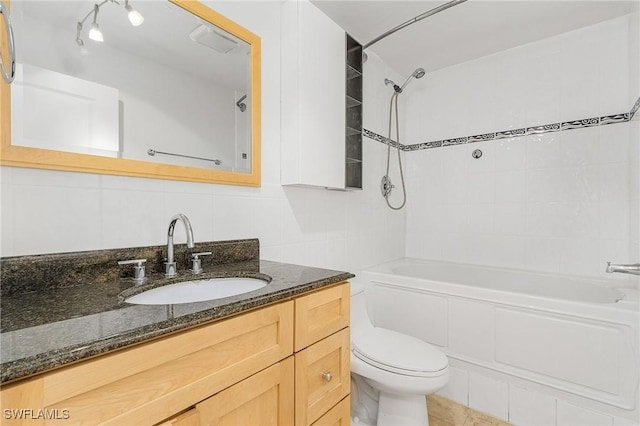 full bathroom featuring toilet, tiled shower / bath, tile walls, vanity, and backsplash