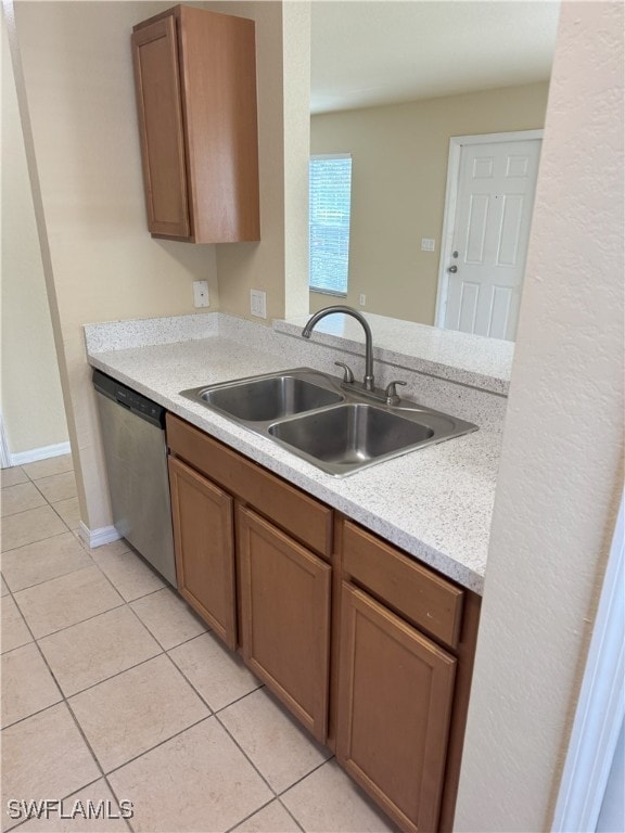 kitchen with sink, light tile patterned floors, stainless steel dishwasher, and kitchen peninsula