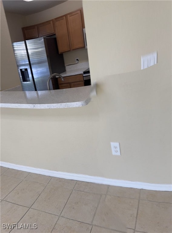 kitchen with stainless steel fridge, sink, and light tile patterned floors