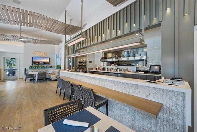 kitchen featuring hardwood / wood-style flooring, decorative backsplash, and a high ceiling