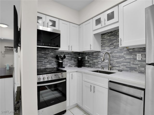 kitchen with sink, light stone counters, white cabinets, stainless steel appliances, and backsplash