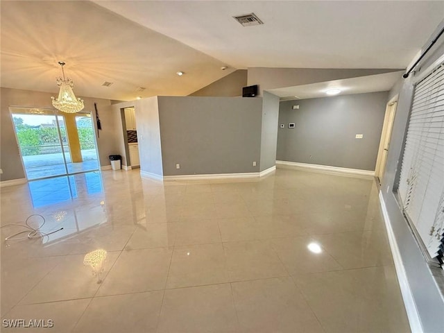 tiled spare room with lofted ceiling and a notable chandelier