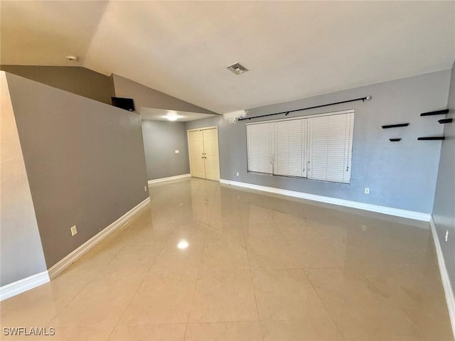 unfurnished room featuring vaulted ceiling and light tile patterned floors