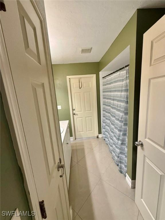 bathroom featuring tile patterned flooring, vanity, a textured ceiling, and a shower with shower curtain