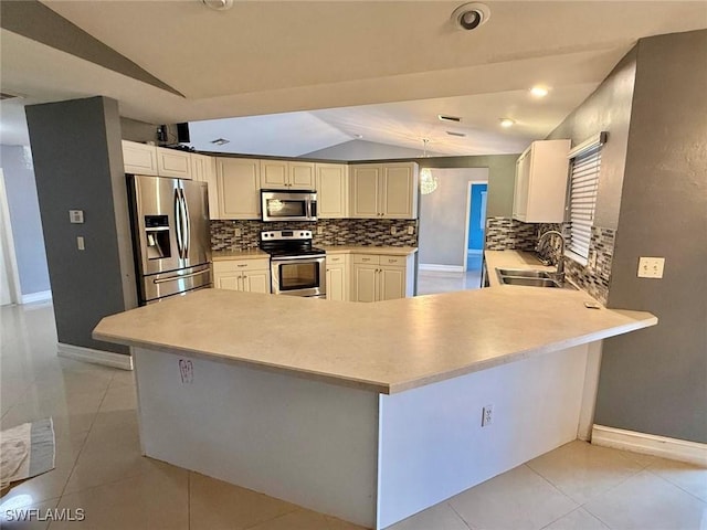 kitchen with vaulted ceiling, stainless steel appliances, kitchen peninsula, and sink