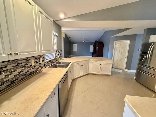 kitchen featuring sink, vaulted ceiling, appliances with stainless steel finishes, white cabinets, and backsplash