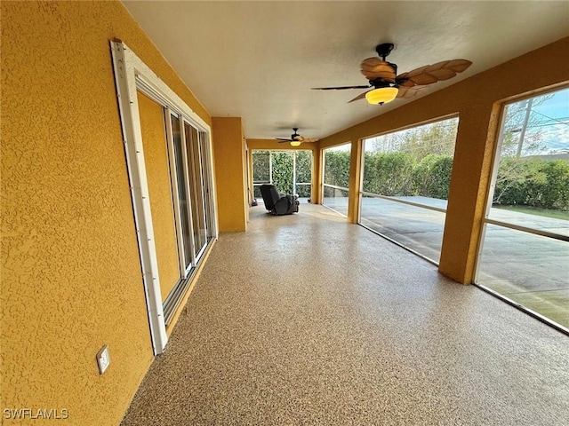 unfurnished sunroom featuring ceiling fan and a healthy amount of sunlight