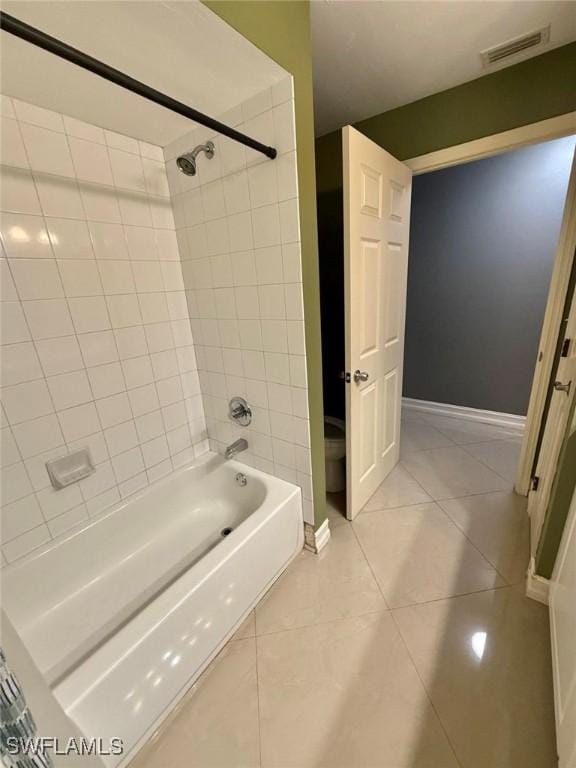 bathroom featuring tile patterned floors, toilet, and tiled shower / bath combo