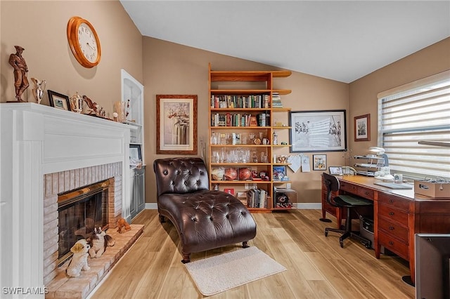 office featuring a fireplace, vaulted ceiling, and light hardwood / wood-style floors