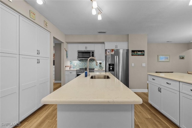 kitchen featuring stainless steel appliances, light hardwood / wood-style floors, and a center island with sink