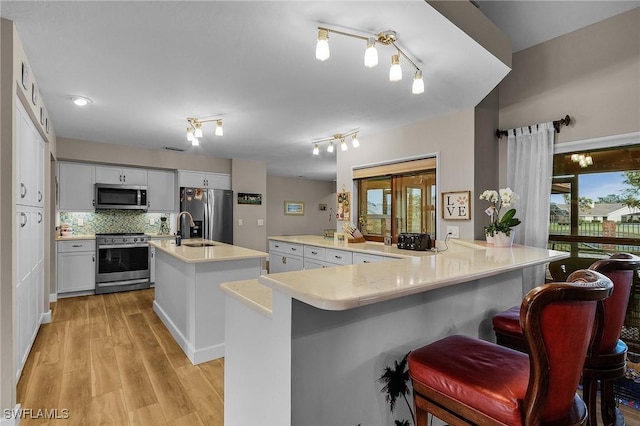 kitchen featuring white cabinetry, tasteful backsplash, a center island with sink, a kitchen breakfast bar, and stainless steel appliances