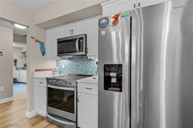 kitchen with decorative backsplash, light hardwood / wood-style flooring, stainless steel appliances, and white cabinets