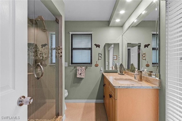 bathroom featuring vanity, a shower with door, and toilet