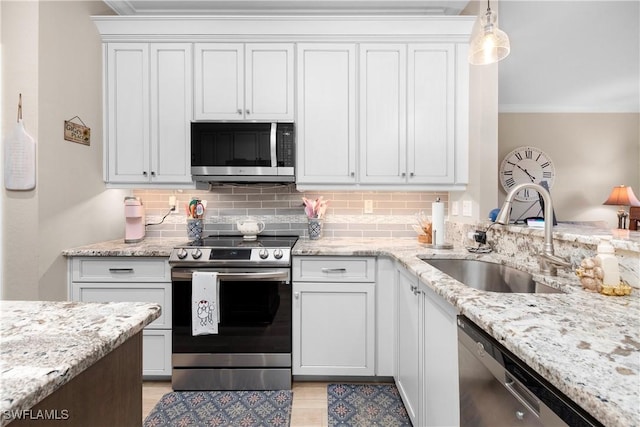 kitchen featuring stainless steel appliances, sink, hanging light fixtures, and white cabinets