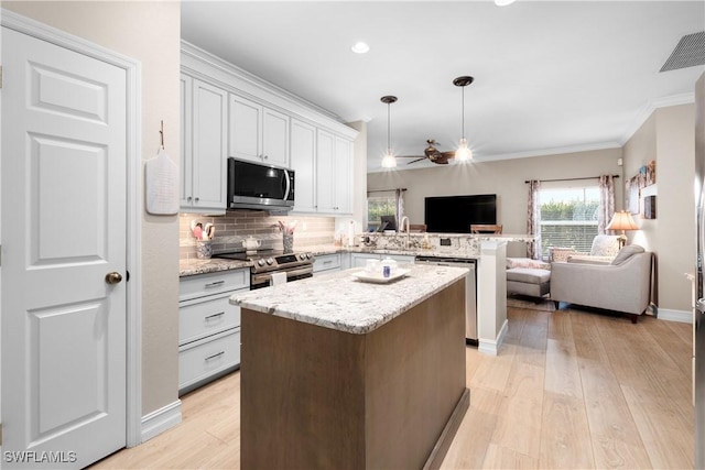 kitchen with a center island, hanging light fixtures, light hardwood / wood-style flooring, appliances with stainless steel finishes, and kitchen peninsula