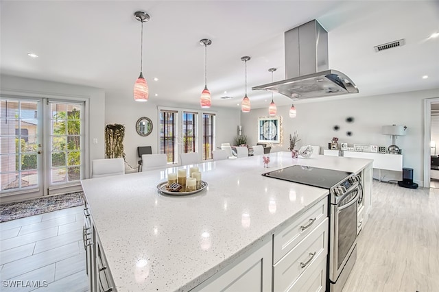 kitchen with white cabinetry, island exhaust hood, hanging light fixtures, and electric range