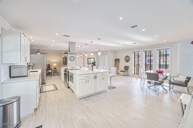 kitchen with a breakfast bar, decorative light fixtures, a center island, appliances with stainless steel finishes, and white cabinets