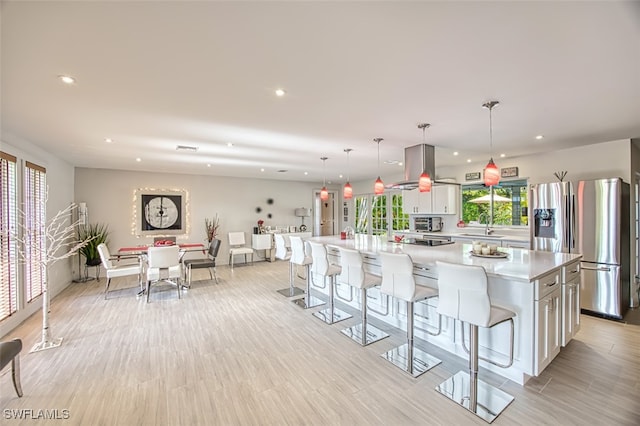 kitchen with white cabinetry, decorative light fixtures, a kitchen island, and stainless steel refrigerator with ice dispenser