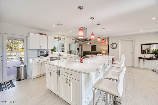 kitchen with a breakfast bar, white cabinetry, a center island, hanging light fixtures, and appliances with stainless steel finishes