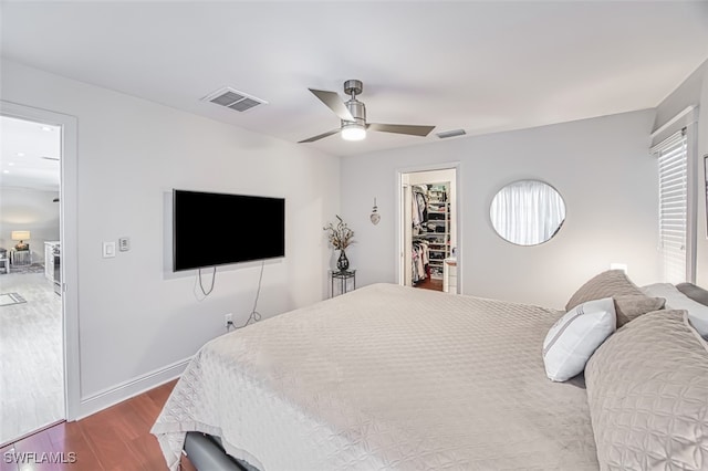 bedroom with hardwood / wood-style flooring, a walk in closet, a closet, and ceiling fan