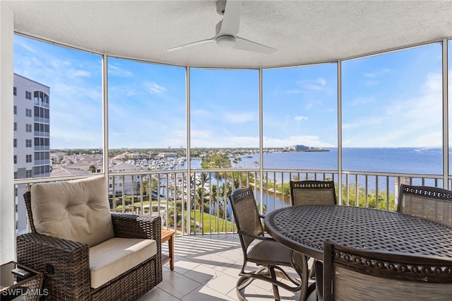 sunroom / solarium featuring a water view and ceiling fan