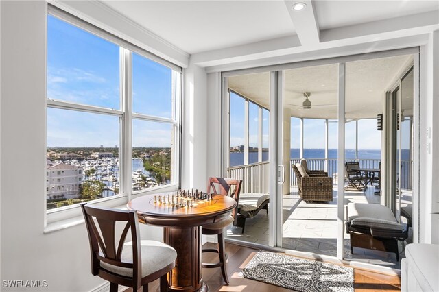 sunroom / solarium featuring a wealth of natural light, a water view, and a ceiling fan