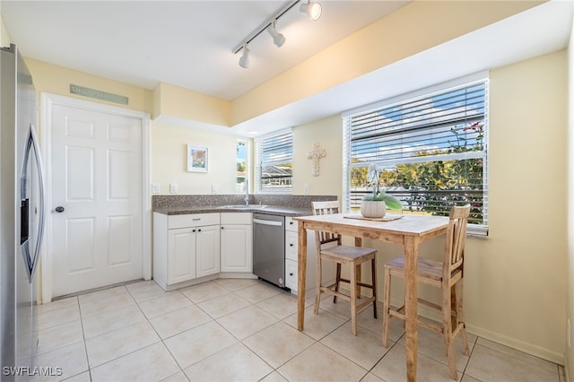 kitchen with appliances with stainless steel finishes, white cabinetry, sink, light tile patterned floors, and track lighting