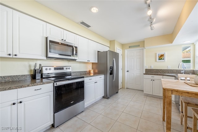 kitchen featuring stainless steel appliances, sink, light tile patterned floors, and white cabinets