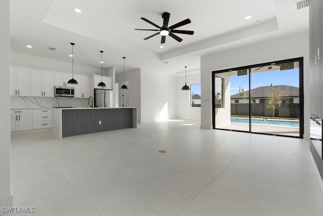 kitchen with white cabinetry, appliances with stainless steel finishes, a kitchen island with sink, and pendant lighting