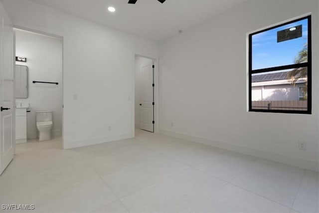 unfurnished bedroom with connected bathroom and light tile patterned floors