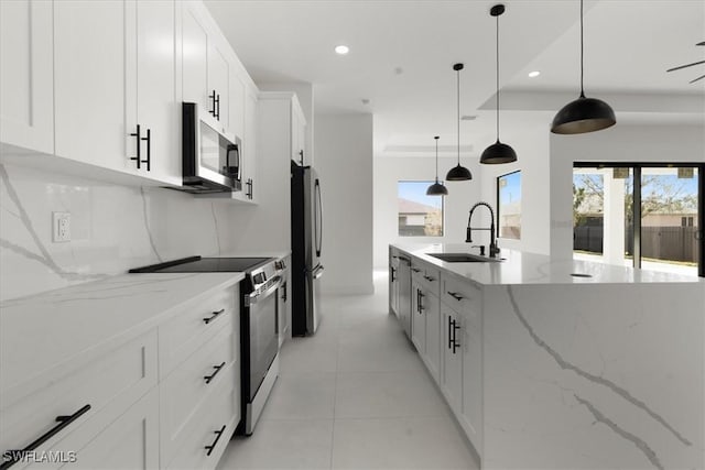 kitchen featuring sink, light stone counters, hanging light fixtures, stainless steel appliances, and white cabinets