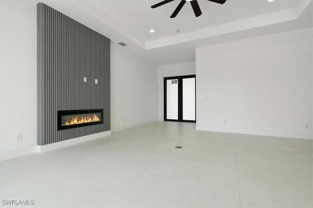 unfurnished living room featuring a raised ceiling and ceiling fan