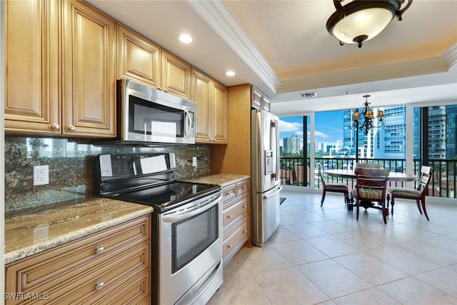 kitchen with a raised ceiling, stainless steel appliances, light stone countertops, and decorative light fixtures