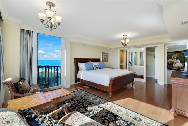 bedroom featuring a water view, an inviting chandelier, dark hardwood / wood-style flooring, and access to outside