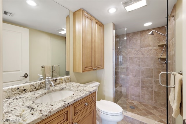 bathroom with vanity, a shower with door, and toilet