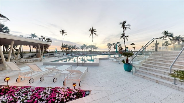 pool at dusk featuring a patio area