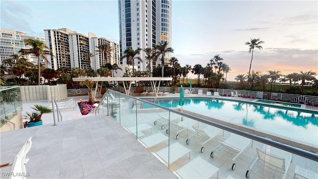 pool at dusk featuring a patio