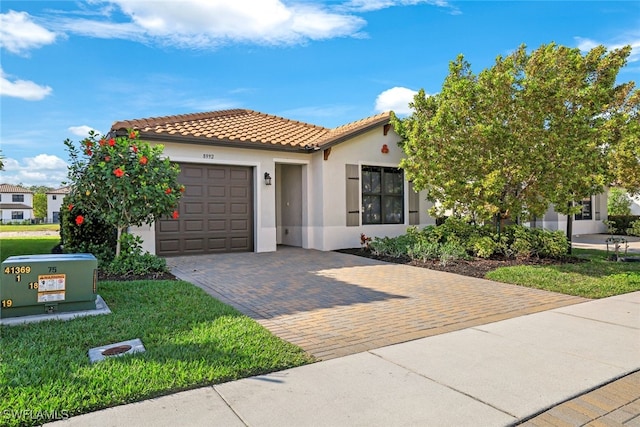 mediterranean / spanish home with stucco siding, decorative driveway, a front lawn, a tile roof, and an attached garage