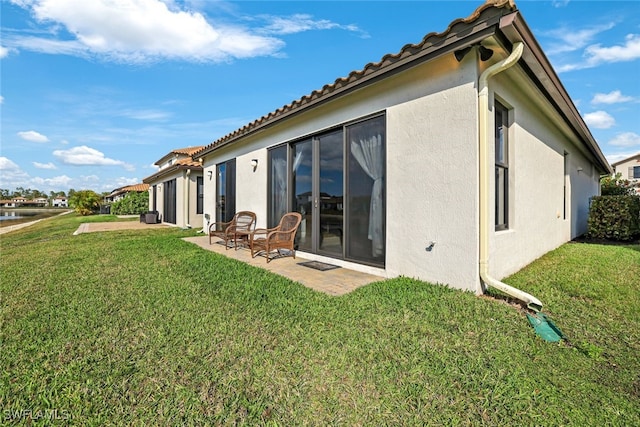 back of property featuring a yard, a tile roof, a patio area, and stucco siding