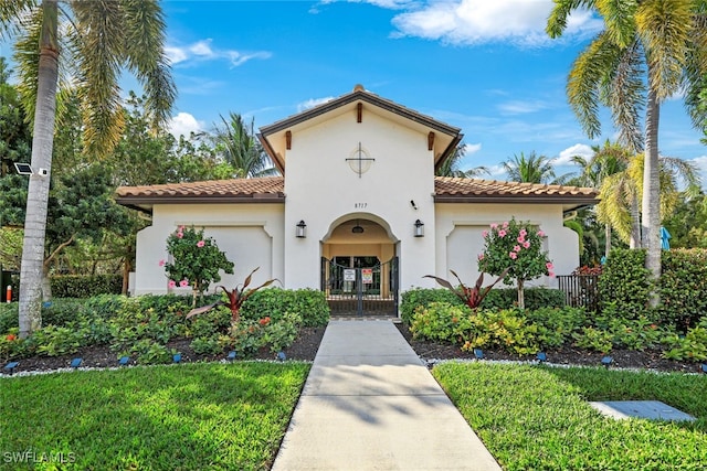 mediterranean / spanish-style home with a tile roof, fence, and stucco siding