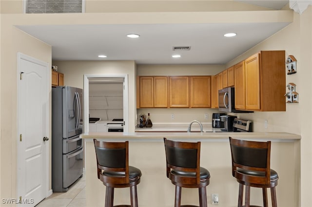 kitchen with appliances with stainless steel finishes, a kitchen breakfast bar, and kitchen peninsula