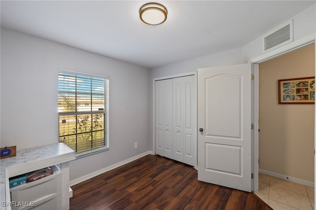 bedroom with dark hardwood / wood-style flooring and a closet