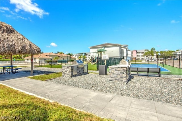 view of home's community featuring a playground, an outdoor kitchen, and tennis court