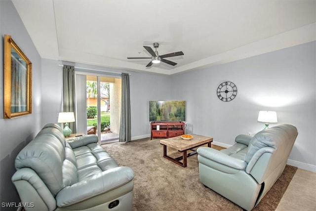 carpeted living room with ceiling fan and a tray ceiling