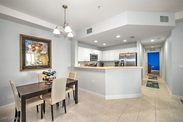 kitchen with white cabinets, hanging light fixtures, a notable chandelier, kitchen peninsula, and stainless steel appliances