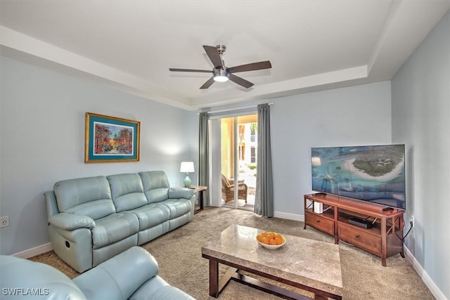 carpeted living room with ceiling fan and a raised ceiling