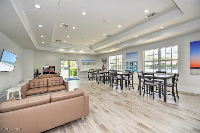 living room with a raised ceiling, crown molding, and light hardwood / wood-style floors