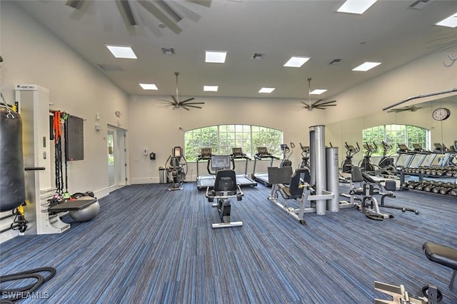 gym featuring ceiling fan, a high ceiling, and dark colored carpet